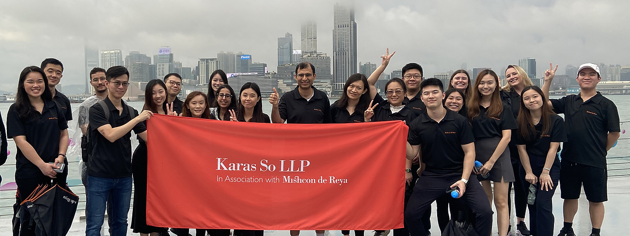 Karas So team holding Karas So LLP banner