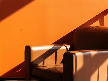 Brown leather armchair in front of orange wall